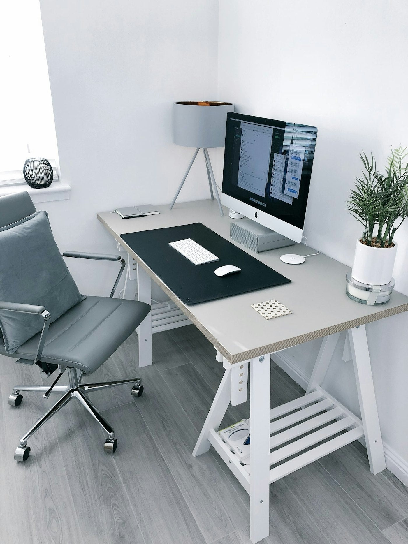 Small corner desk setup with desk mat, monitor and plant
